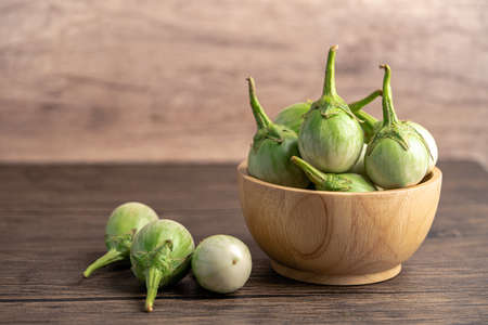 Green eggplant fresh vegetable in wooden bowl with copy space.の写真素材