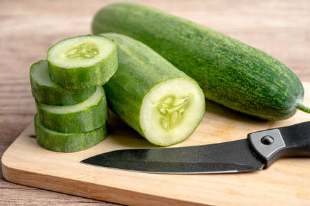 Cucumber vegetable food cut in slice and knife on cutting board for cooking in kitchen.の写真素材