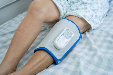 Asian senior or elderly old woman patient with Cordless Air Compression Pressure Leg Massage on the bed in nursing hospital.の写真素材