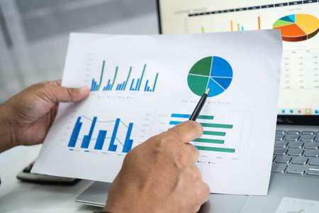 Asian accountant working and analyzing financial reports project accounting with chart graph in modern office, finance and business concept.の写真素材
