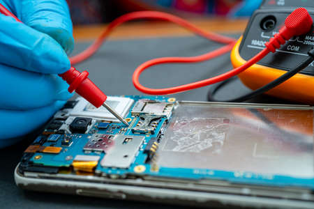 Technician repairing inside of mobile phone by soldering iron. Integrated Circuit. the concept of data, hardware, technology.の写真素材