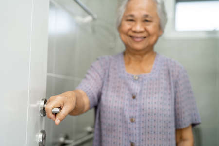 Asian senior elderly old lady woman patient open toilet bathroom by hand in nursing hospital ward, healthy strong medical concept.の写真素材