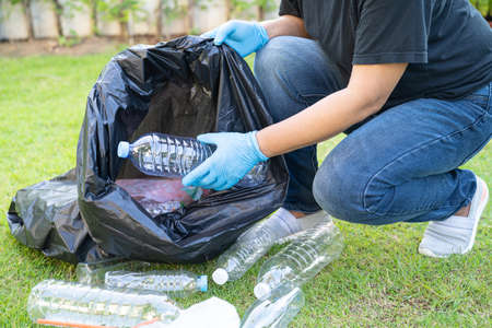 Asian woman volunteer carry water plastic bottles into garbage bag trash in park, recycle waste environment ecology concept.の写真素材