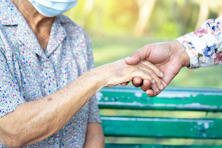Caregiver daughter holding Touching hands Asian senior or elderly old lady woman patient with love, care, helping, encourage and empathy at nursing hospital ward, healthy strong medical concept.の写真素材