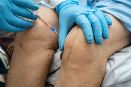Asian doctor inject Hyaluronic acid platelet rich plasma into the knee of senior woman to walk...