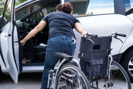 Asian woman folding and lift up wheelchair into her car. Accessibility concept.の写真素材