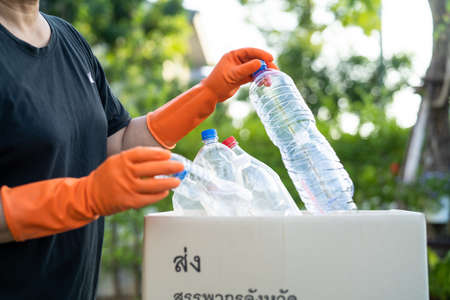 Asian woman volunteer carry water plastic bottles into garbage box trash in park, recycle waste environment ecology concept.の写真素材