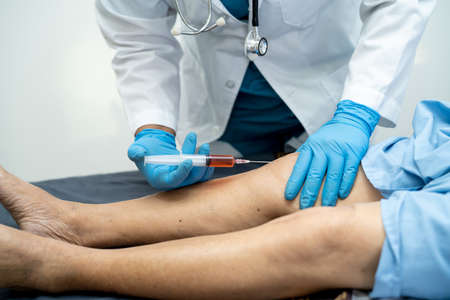 Asian doctor inject Hyaluronic acid platelet rich plasma into the knee of senior woman to walk without pain.の写真素材