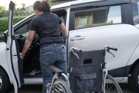 Asian woman folding and lift up wheelchair into her car. Accessibility concept.