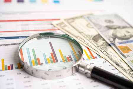 Magnifying glass on charts graphs paper with US dollar banknotes. Financial development, Banking...