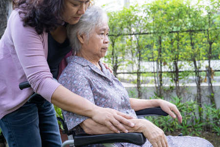 Caregiver daughter help Asian senior or elderly old lady woman on electric wheelchair in park.の写真素材