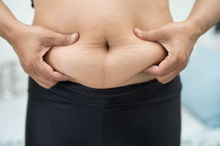 Overweight Asian woman show fat belly at office.の写真素材