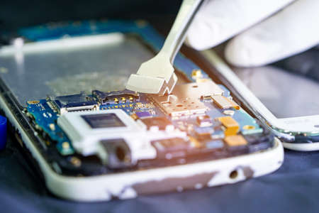 Technician repairing inside of mobile phone by soldering iron. Integrated Circuit. the concept of data, hardware, technology.の写真素材