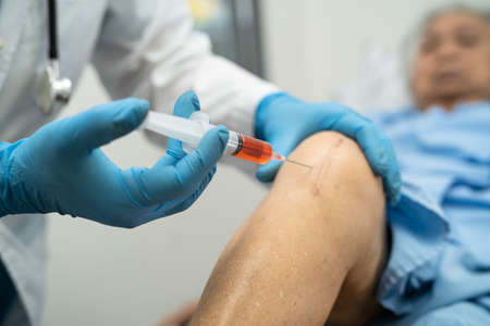 Asian doctor inject Hyaluronic acid platelet rich plasma into the knee of senior woman to walk without pain.の写真素材