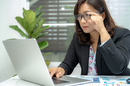 Asian accountant type keyboard to enter information, working, calculate and analyzing report project accounting with notebook in modern office, finance and business concept.の写真素材