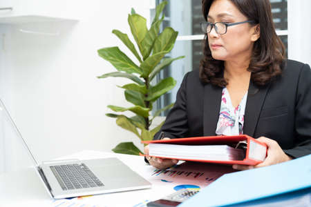 Asian accountant working and analyzing financial reports project accounting with chart graph and...
