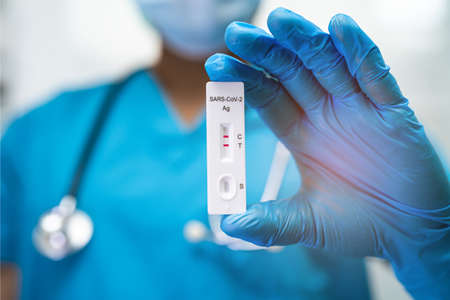 Asian doctor in PPE suit show positive test result with Saliva Antigen Test Kit for check Covid-19...