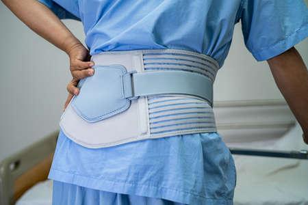Asian lady patient wearing back pain support belt for orthopedic lumbar with walker.