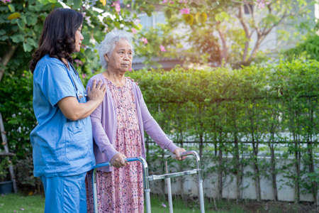 Doctor help and care Asian senior or elderly old lady woman use walker with strong health while walking at park in happy fresh holiday.の写真素材