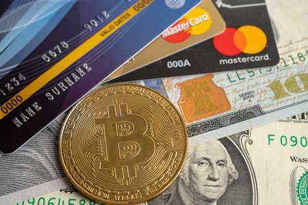 Bangkok, Thailand, July 9, 2021, Gold bitcoin with credit card on US dollar banknotes for electronic...