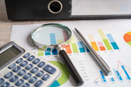 Magnifying glass and calculator on charts graphs paper. Financial development, Banking Account, Statistics, Investment Analytic research data economy, Stock exchange trading, Business office concept.の写真素材
