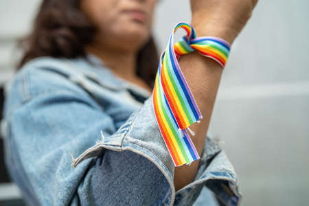 Asian lady wearing rainbow flag wristbands, symbol of LGBT pride month celebrate annual in June social of gay, lesbian, bisexual, transgender, human rights.の写真素材