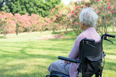 Asian senior or elderly old lady woman patient sitting and happy on wheelchair in park, healthy strong medical concept.の写真素材