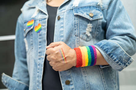 Asian lady wearing rainbow flag wristbands, symbol of LGBT pride month celebrate annual in June social of gay, lesbian, bisexual, transgender, human rights.の写真素材