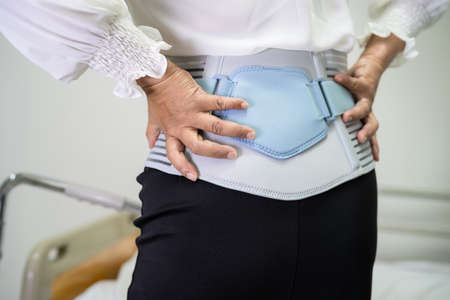Asian lady patient wearing back pain support belt for orthopedic lumbar with walker.