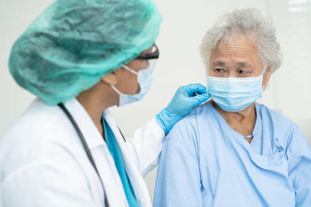 Doctor help Asian senior or elderly old lady woman patient wearing a face mask in hospital for protect safety infection and kill Covid-19 Coronavirus.の写真素材