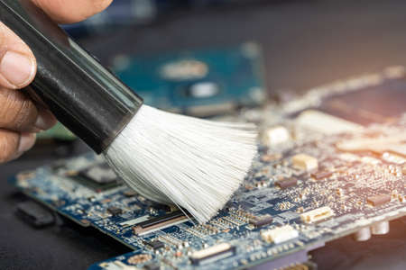 Technician use brush and air blower ball to clean dust in circuit board computer. Repair upgrade and maintenance technology.の写真素材