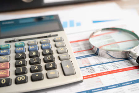 Magnifying glass and calculator on charts graphs paper. Financial development, Banking Account,...