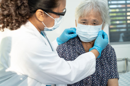 Asian doctor wearing face shield and PPE suit new normal to check patient protect safety infection Covid 19 Coronavirus outbreak at quarantine nursing hospital ward.の写真素材