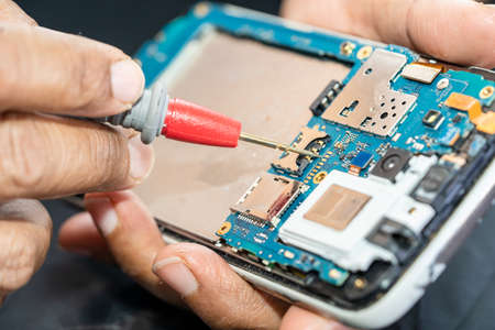 Technician repairing inside of mobile phone by soldering iron. Integrated Circuit. the concept of...