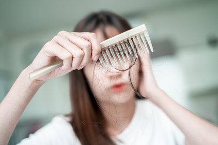 Asian woman have problem with long hair loss attach to comb brush.の写真素材