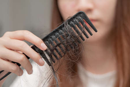 Asian woman have problem with long hair loss attach to comb brush.の写真素材