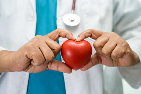 Doctor holding a red heart in hospital ward, healthy strong medical concept.の写真素材