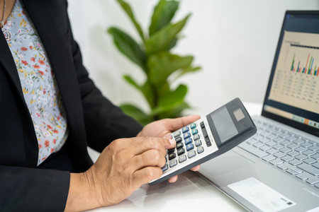 Asian accountant working and analyzing financial reports project accounting with labtop and calculator in modern office, finance and business concept.の写真素材