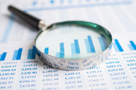 Magnifying glass on chart graph spreadsheet paper. Financial development, Banking Account, Statistics, economy, Stock exchange trading, Business office company meeting concept.の写真素材