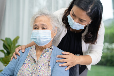 Help Asian senior or elderly old lady woman sitting on wheelchair and wearing a face mask for protect safety infection Covid19 Coronavirus.の写真素材