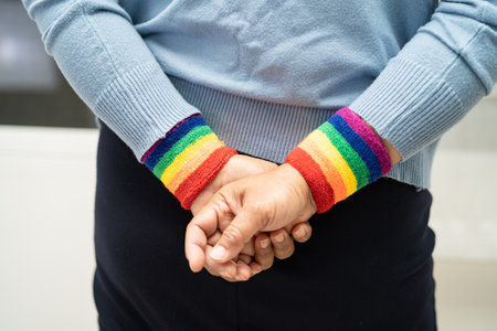 Asian lady wearing rainbow flag wristbands, symbol of LGBT pride month celebrate annual in June...