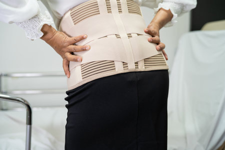 Asian lady patient wearing back pain support belt for orthopedic lumbar with walker.の写真素材