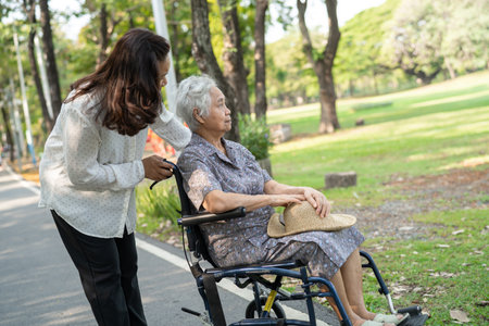 Caregiver help and care Asian senior or elderly old lady woman patient sitting and happy on wheelchair in park, healthy strong medical concept.の写真素材