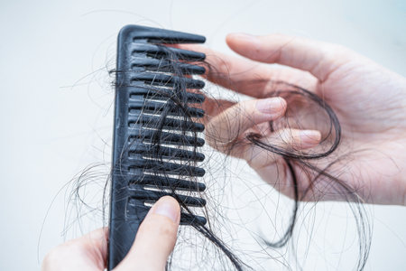 Asian woman have problem with long hair loss attach to comb brush.の写真素材