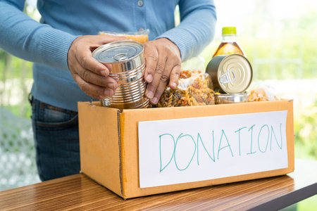 Volunteers putting various dry food in donation box for help people.の写真素材