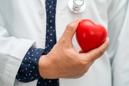 Doctor holding a red heart in hospital ward, healthy strong medical concept.の写真素材