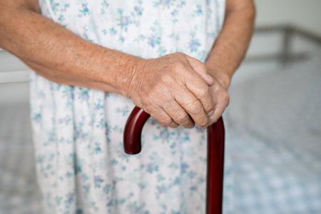 Asian elderly disability woman holding waling stick, wood cane, round handle, walking aid for help to walk.の写真素材