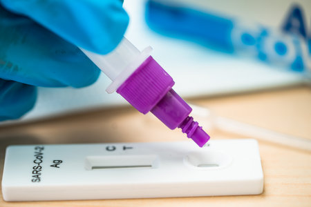 Asian doctor holding Saliva Antigen Test Kit for check Covid19 coronavirus in hospital.