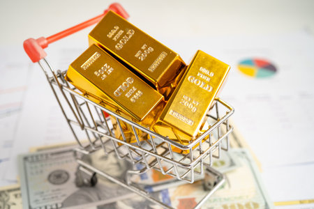 Gold bar in shopping cart on US dollar banknotes money and graph, economy finance exchange trade investment concept.の写真素材