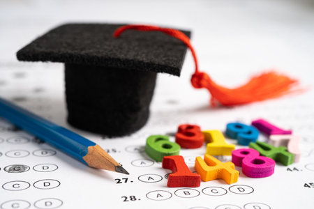 Graduation gap hat and pencil on answer sheet background : Education study testing learning teach...